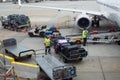 Trolley full of bags, suitcases and other luggage being loaded by ground crew