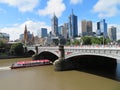 Melbourne cityscape with modern buildings and a boat under the bridge