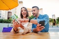 Mele and female having fun sharing media with a mobile phone. Friends watching a smartphone on a coffee shop terrace Royalty Free Stock Photo