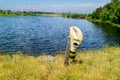 Melee weapons a large knife stuck in the ground on the handle hanging gas mask background plant and pond