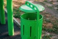 A mellifluous green trash can in the park. New, minimalist trash can. Environmental protection. Space for text
