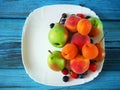 Mellow fresh summer fruits and berries mix in white plate on green wooden background with copy sapce, strawberries, blueberries, Royalty Free Stock Photo