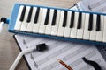 Melodica prepared for the music study with sheet music below Royalty Free Stock Photo