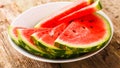 Melon cut in a white plate, placed on a wooden table