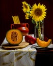 A melon in half and a slice on a plate with two red apples, sunflowers and raw spaghetti, against a dark background Royalty Free Stock Photo