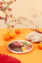 Melon seeds, sunflower seeds, gummy candy, salted dried fruit and jam are displayed on a round ceramic plate. Tangerines, a stone