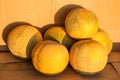 Melons of the Kolkhoznitsa variety are yellow in color with a beautiful grid pattern, located in bulk on the shelf. Vegetables, he