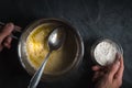 Melted butter in a ladle and a bowl of flour in a hand