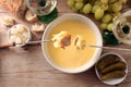 Melted cheese fondue with bread on long forks, pickles, grapes and white wine on a rustic wooden table, copy space, high angle Royalty Free Stock Photo