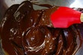 Melted chocolate with a red spatula in a metal bowl