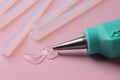 Melted glue dripping out of hot gun nozzle near sticks on pink background, closeup Royalty Free Stock Photo