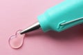 Melted glue dripping out of hot gun nozzle on pink background, closeup Royalty Free Stock Photo