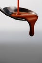 Melted milky brown chocolate pouring from a spoon, isolated on white close up Royalty Free Stock Photo