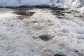 Melted snow on a country road with mud and snow around the edges with tire treads. Puddles on a snowy road in early spring Royalty Free Stock Photo