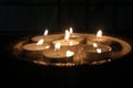 Melted wax tealight candles or diya lamps glowing in dark night. candles arranged in rows in darkness. Royalty Free Stock Photo