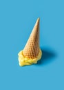 Melted yellow ice cream cone creative pastel blue background