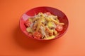 Melting cheddar cheese over the top of french fries covered in spicy sauce with meat and tomatoes. Orange background.