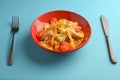 Melting cheddar cheese over the top of french fries covered in spicy sauce with meat and tomatoes. Blue background.