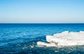 Melting ice chunks floating into blue water under empty sky. Royalty Free Stock Photo