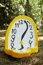 Melting clock art object lying on forest ground outdoor art exhibition, atmospheric surreal concept