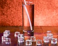 Melting cubes of transparent cold ice and a glass of soda with cocktail straw