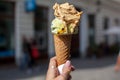 Melting delicious ice cream in waffle cone gelato pistachio salty caramel holding female hand Royalty Free Stock Photo