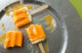 Melting and eaten dreamsicles on a galvanized steel platter, on a green background shot directly above, top view. Royalty Free Stock Photo