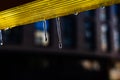 Melting icicles on a bright yellow plastic roof in bright light Royalty Free Stock Photo