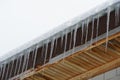 Melting icicles hanging from a snow covered roof at thaw weather