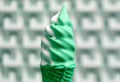 Melting Mint Green and White Colored Soft Serve Ice Cream Cone against Blurry Modern Concrete Wall