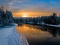 Melting river in winter with water reflecting sunlight, snowy forest  around Royalty Free Stock Photo