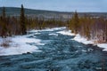 Melting snow and flowing cold blue river in the snow next to the forest. Arrival of spring Royalty Free Stock Photo
