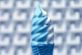 Melting White and Blue Soft Serve Ice Cream Cone on Blurry Modern Concrete Wall Background