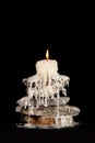 Melting white candle standing on the rocks on a black backgrounds