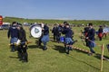 Members of a Marching Pipe band climbing over the temporary red and white tape barrier after their performance.