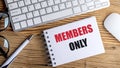 Members only message on notepad placed on wooden table with keyboard, pen and glasses Royalty Free Stock Photo