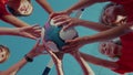 Players of youth football team stand in circle holding ball against football goal and sky