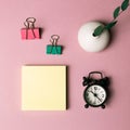 Memo pad, clip, clock, vase of green leaf on pink background Royalty Free Stock Photo