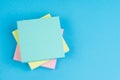 Memo, reminder or business idea and important quote, stack of sticky notes on solid blue background with pink, yellow and blue on