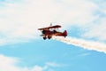 Memorial Airshow. Red Stearman biplane flying towards camera while trailing smoke in exhibition