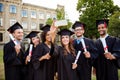 Memories of six international cheerful graduates, posing for shot, attractive brunette lady is taking, wearing gowns and mortar b