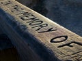 In Memory of Bench rail carved in wood in afternoon sun