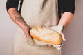A men in an apron holds various fresh bread loaves with golden crisp in her hands. Homemade alternative bread