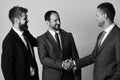 Men with beard and smiling faces make successful deal. CEOs shake hands on light grey background. Business and Royalty Free Stock Photo