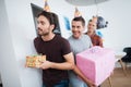 Men in birthday hats are preparing a surprise birthday party. They are preparing to meet the birthday girl. Royalty Free Stock Photo