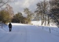 Men in black clothes with backpack walking on snow covered asphalt road in winter forest Royalty Free Stock Photo