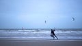 Men in black suits go kitesurfing.Extreme sports,kiteboarding on vacation on sandy beach in windy weather.Beautiful foto in cloudy