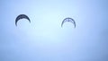 Men in black suits go kitesurfing.Extreme sports,kiteboarding on vacation on sandy beach in windy weather.Beautiful foto in cloudy