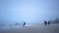 Men in black suits go kitesurfing.Extreme sports,kiteboarding on vacation on sandy beach in windy weather.Beautiful foto in cloudy