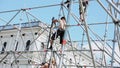 Men building stage for event on street. Workers raise ladder. Iron balks. Sunny